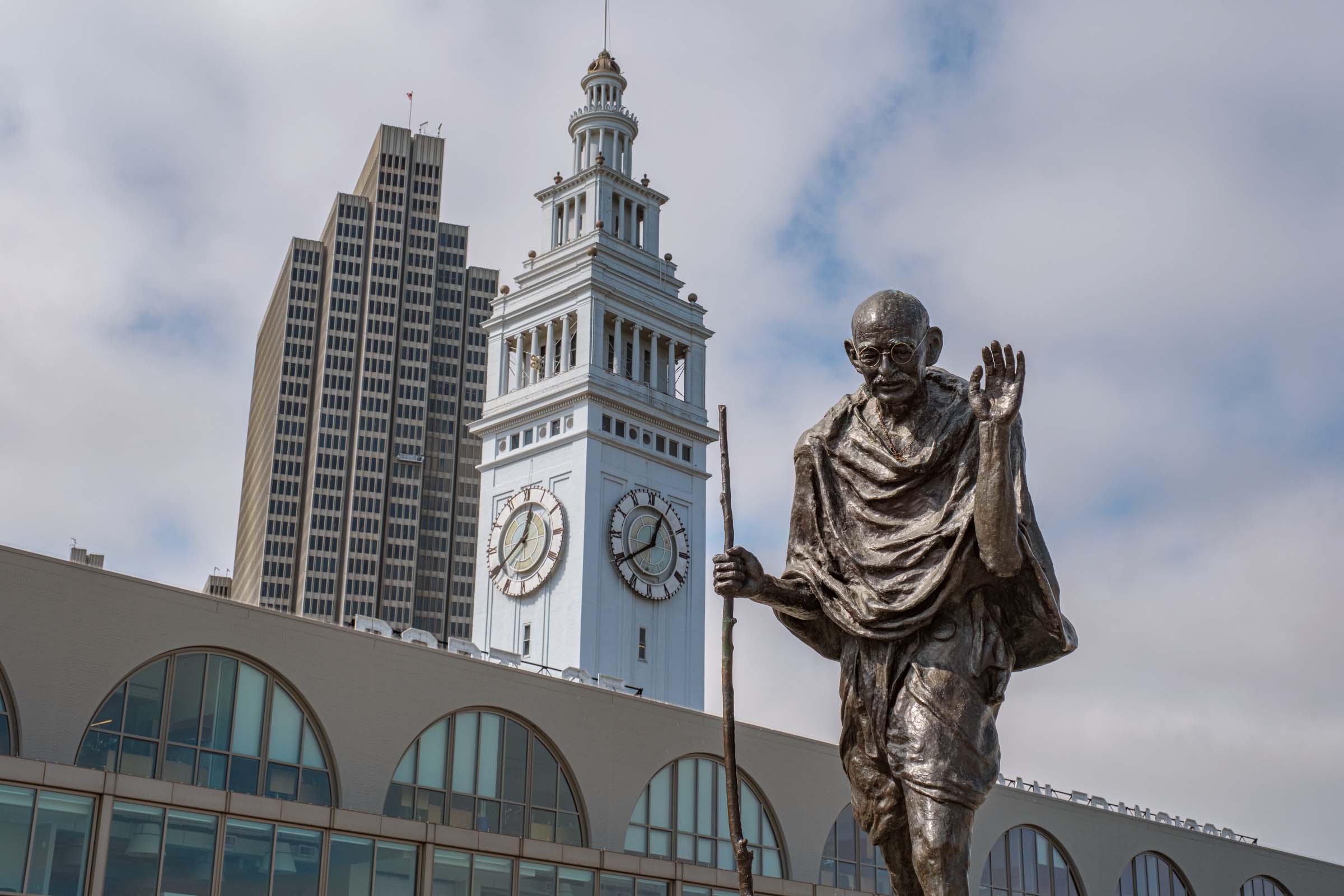 bronze sculpture of Mahatma Gandhi with the San Francisco Ferry Terminal tower in the background