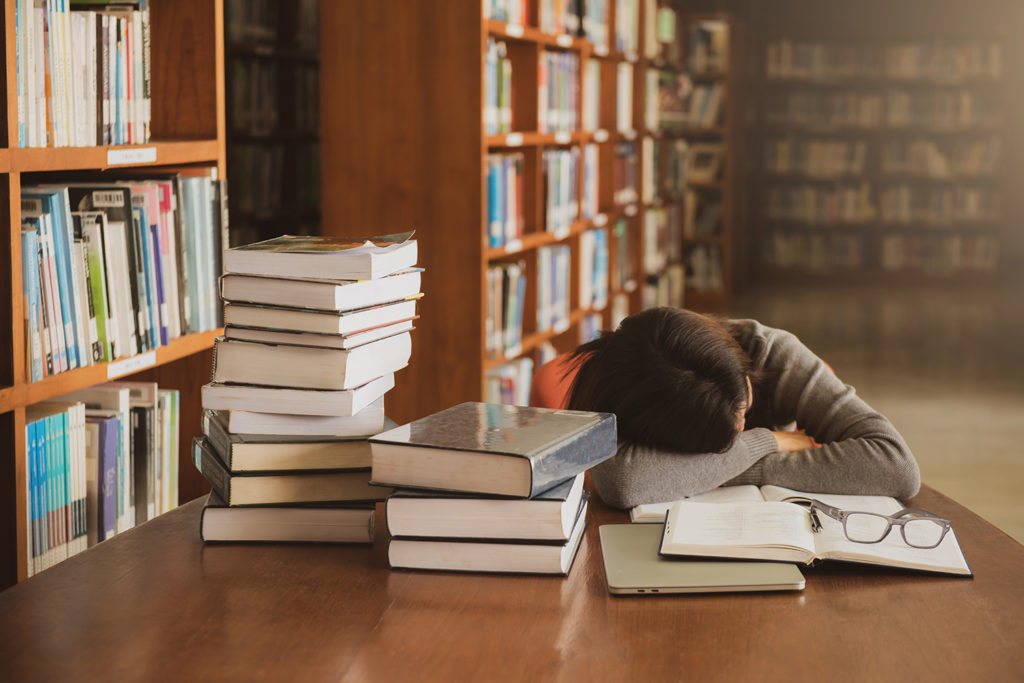 lawyer sleeping at a table covered with books in a library