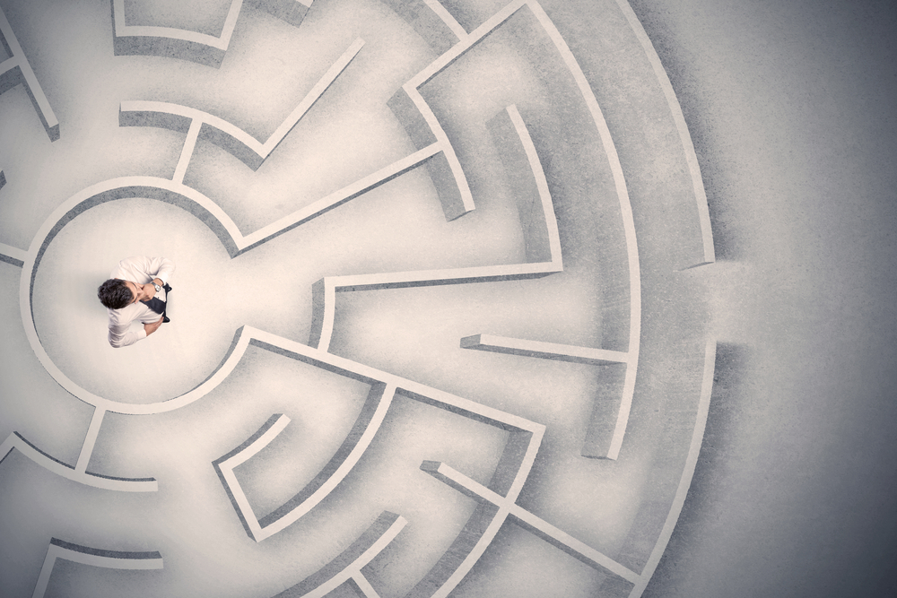 a lawyer standing at the center of a labyrinth, shot from overhead