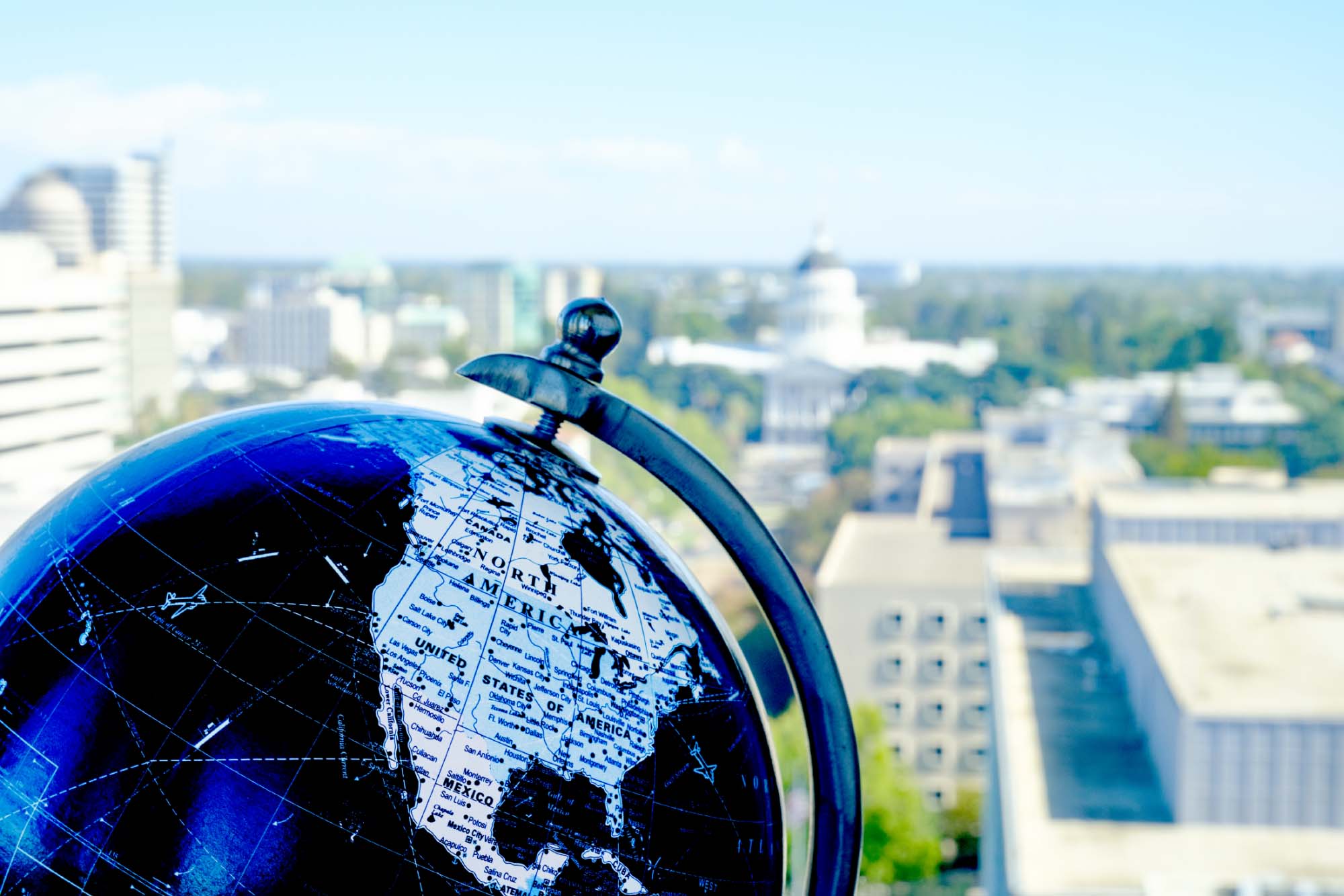 globe in front of window looking out at the California State Capitol building