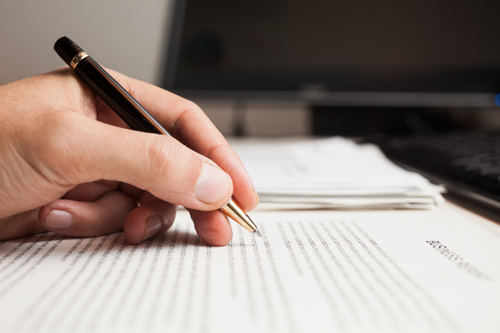 hand holding a pen while reviewing printed page