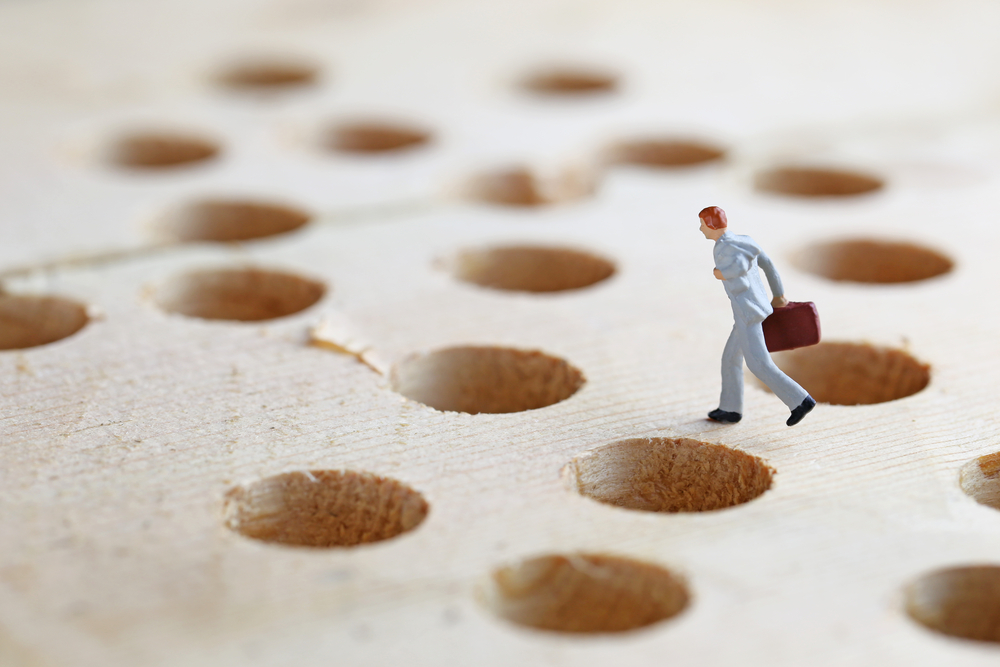 1:150 scale figure of a business person running across a board full of holes