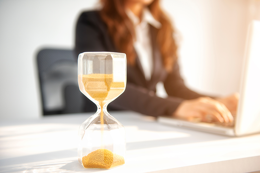 lawyer working on laptop with hourglass in the foreground