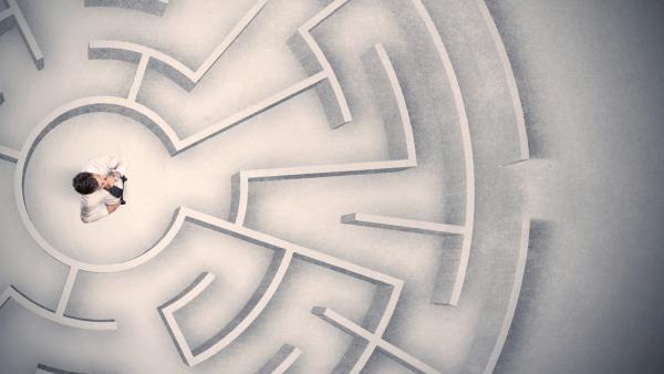 a lawyer standing at the center of a labyrinth, shot from overhead