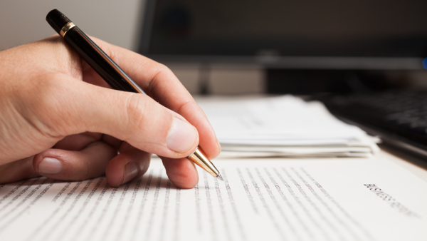 hand holding a pen while reviewing printed page